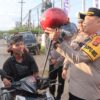 Pendekatan Holistik, Polres Kutim Bagi Helm dan Bunga Untuk Pengguna Jalan